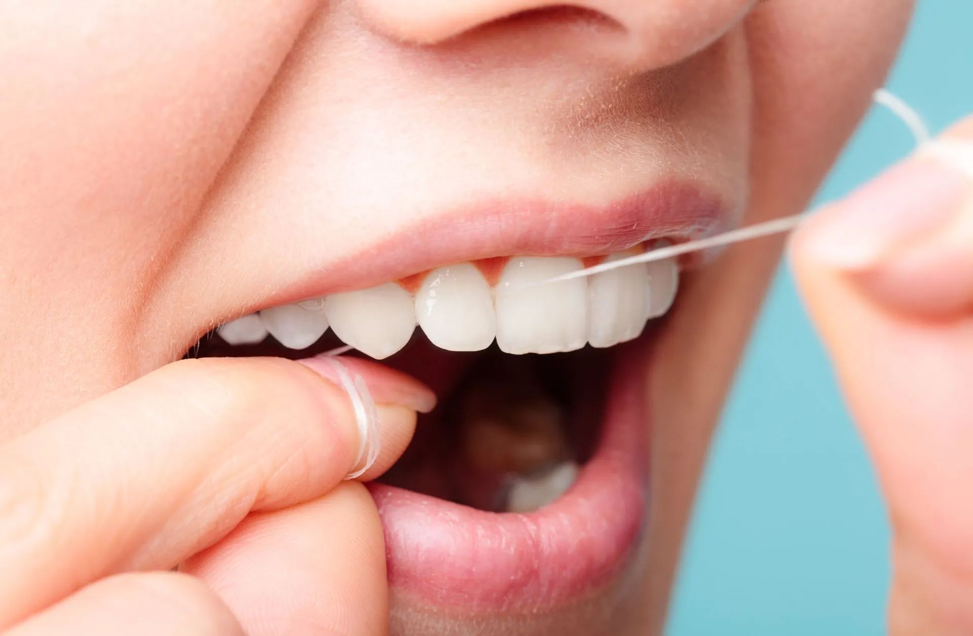 Pessoa usando fio dental para uma higiene bucal completa.
